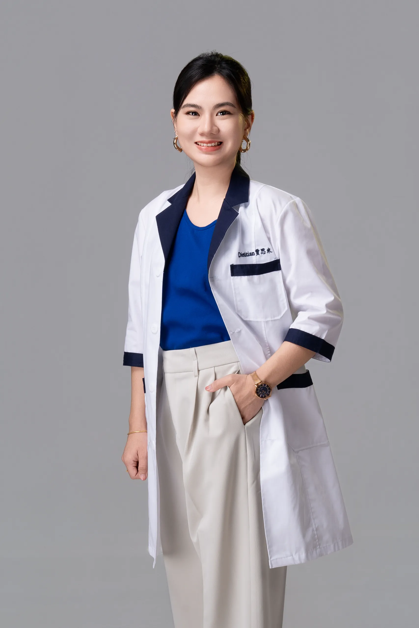 Jaceme Chuah standing in her dietitian coat, smiling with one hand in her pocket