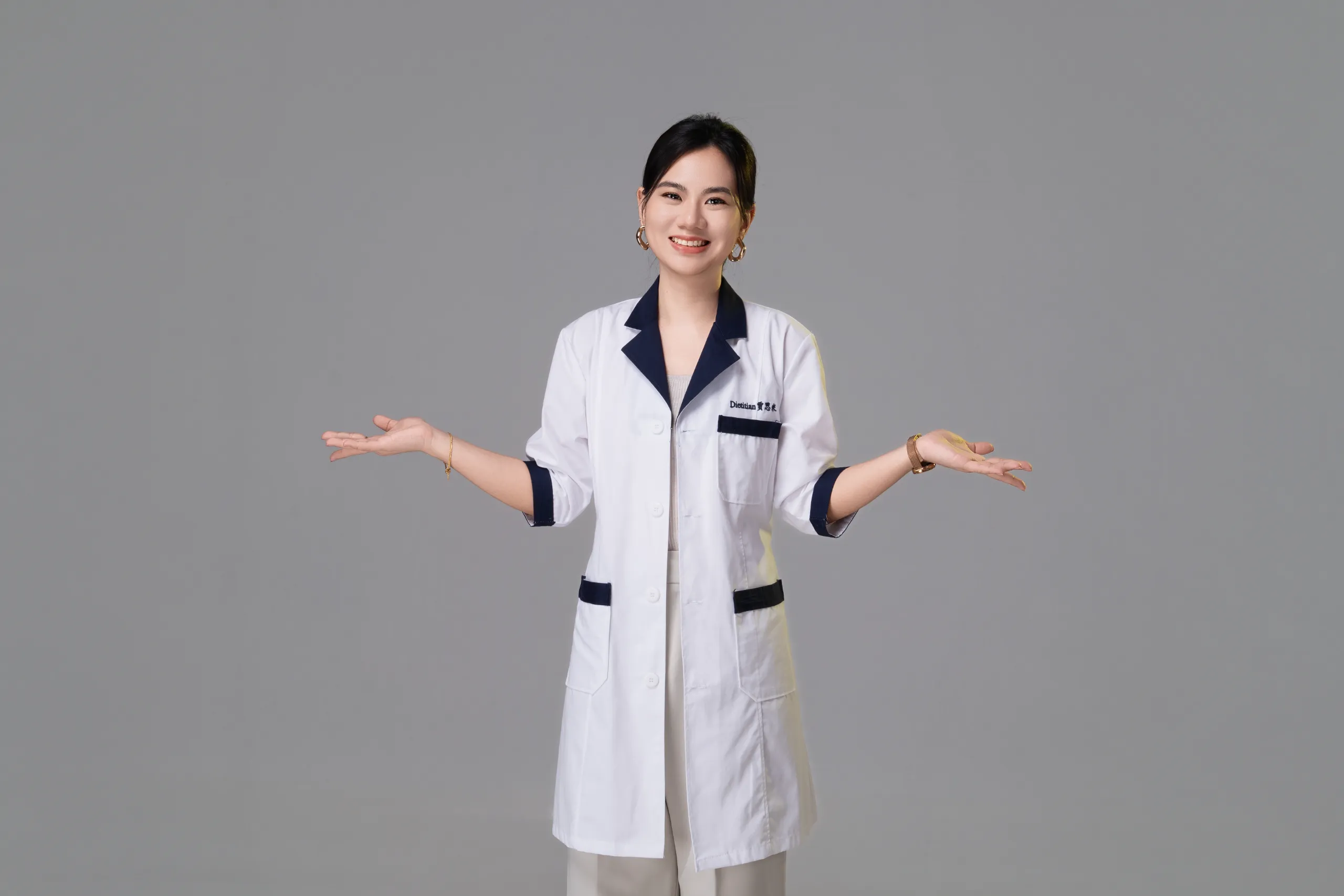 Jaceme Chuah presenting with open hands, in her dietitian coat