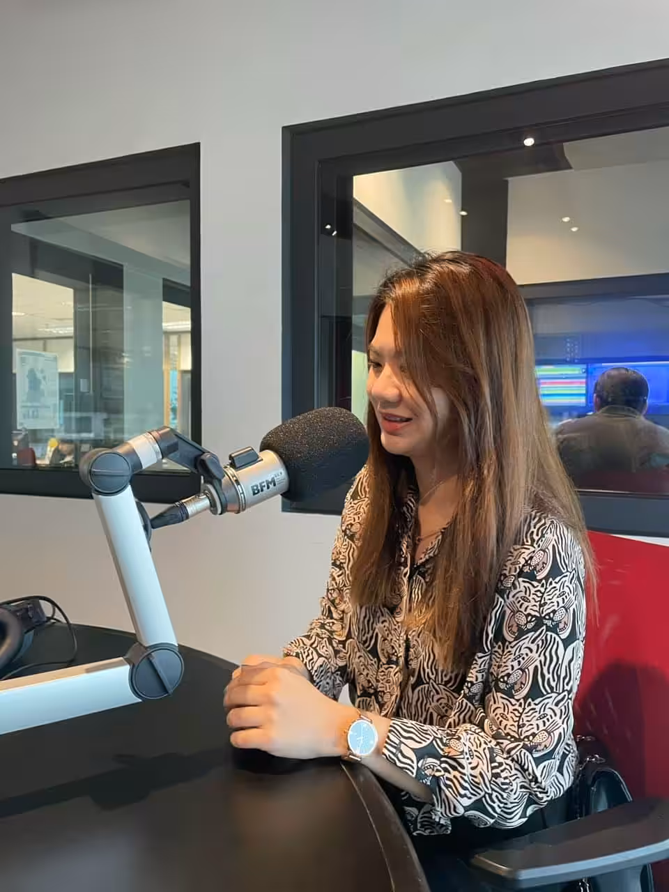 Jaceme Chuah speaking into a microphone during a radio interview
